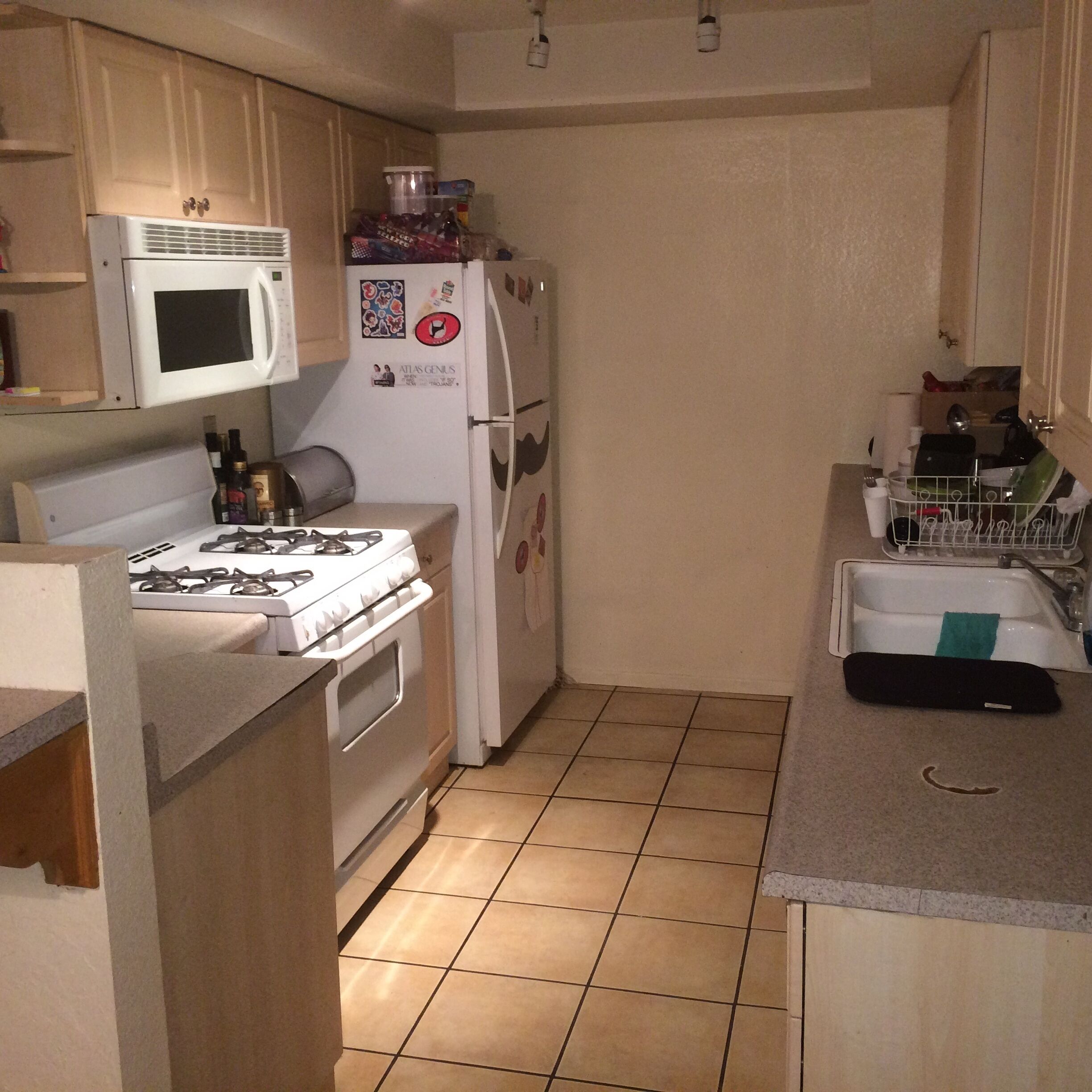 A compact kitchen with a stove, microwave, refrigerator, and a sink.
