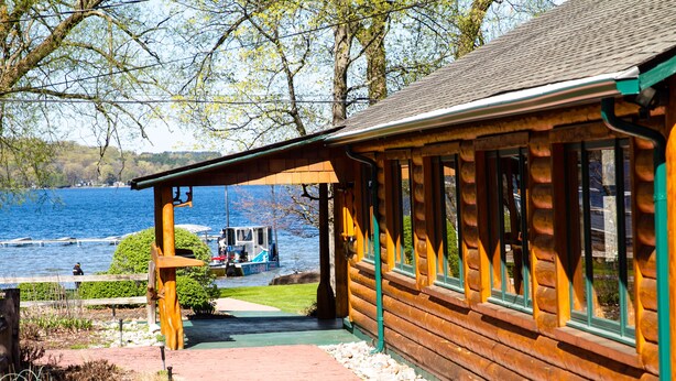 Una cabaña de madera con un porche cubierto que da a un lago.