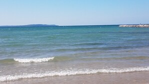 Una playa con aguas tranquilas y un rompeolas rocoso.
