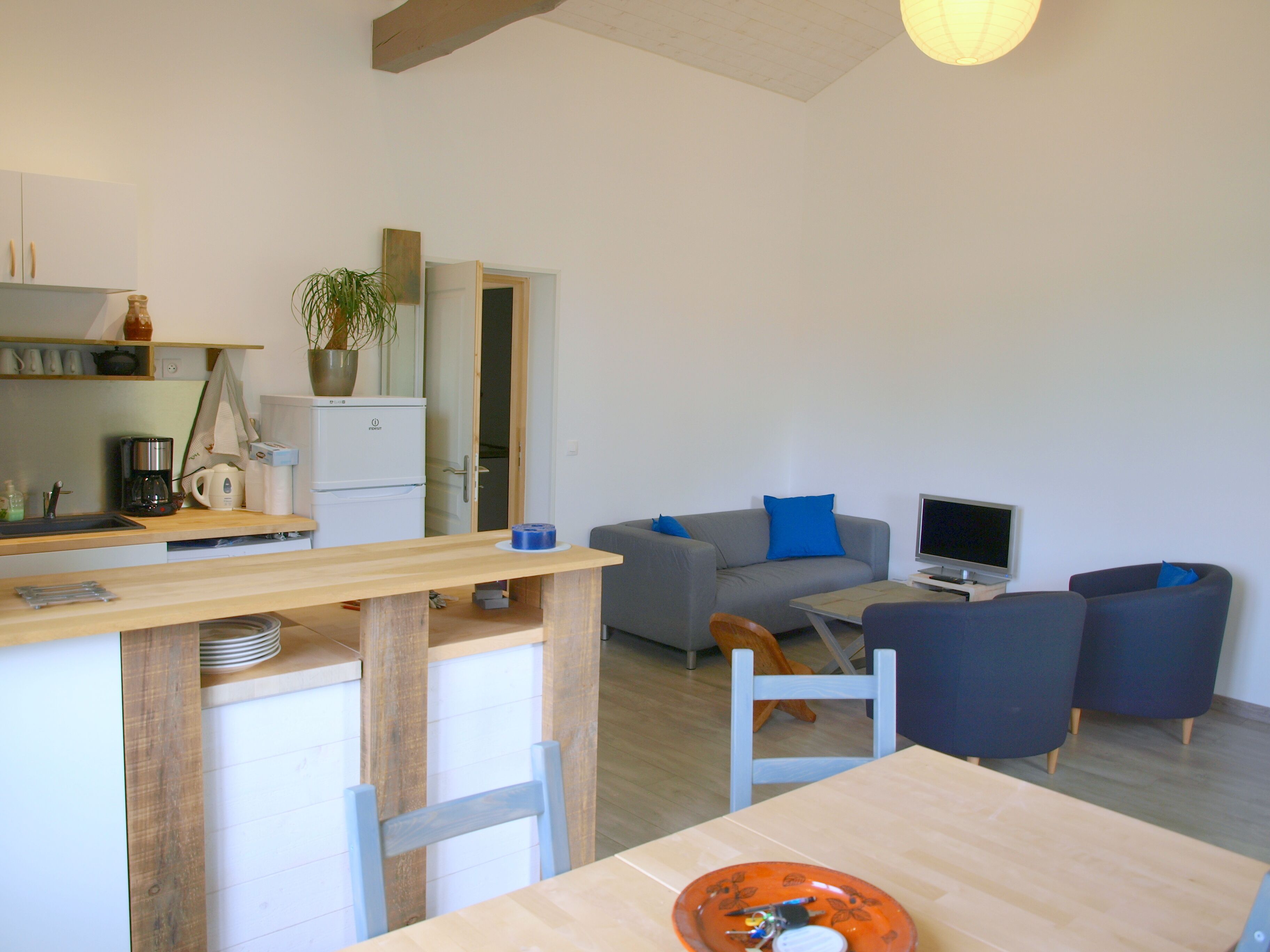 Un espacio habitable compacto con kitchenette, comedor y zona de estar con televisor.
