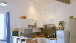Une cuisine compacte avec des poutres en bois, un lave-linge, un four à micro-ondes et un évier.