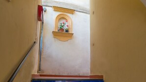 Un escalier aux marches bleues menant à un palier doté d’une petite fenêtre et d’une plante en pot.