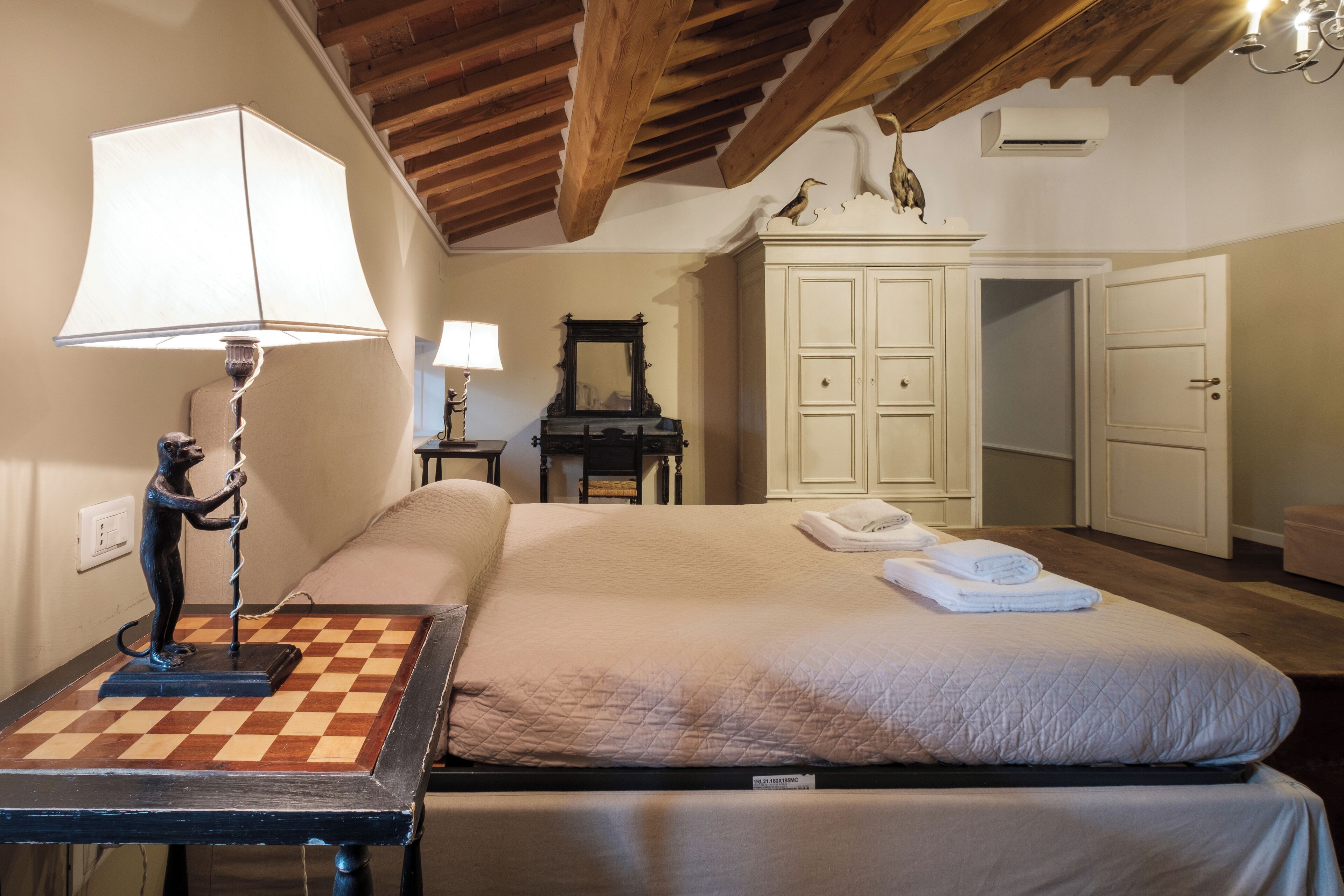 Un dormitorio con una cama, una lámpara, un tocador y un espejo.