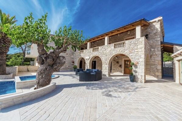 A stone building with a courtyard, outdoor seating, and a water feature.
