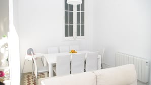 Un coin repas aux murs blancs, avec une table et des chaises, une fenêtre et un radiateur.