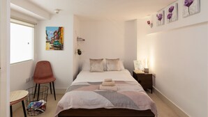 A bedroom with a bed, a chair, a bedside table, a wall-mounted picture, and a window. - A Stylish 2 Bed, 2 Bath London Apartment (London)