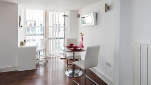 A modern dining area with a glass table, white chairs, and a red vase. - A Stylish 2 Bed, 2 Bath London Apartment (London)