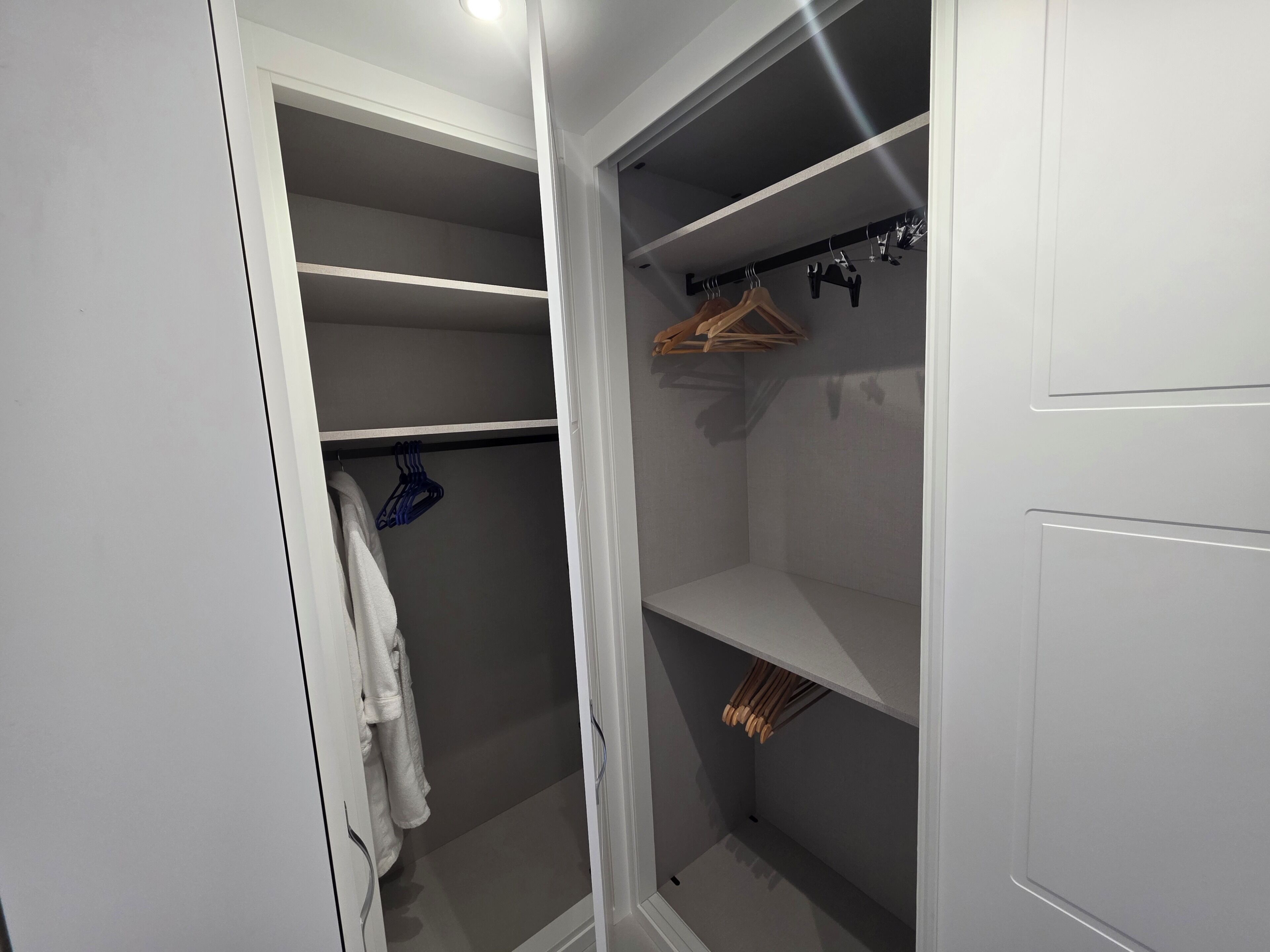 A walk-in closet with open shelves, a hanging rod, and a robe draped over a door.