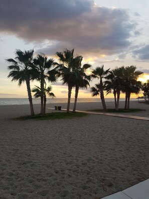 Een strand met palmbomen en een ondergaande zon.