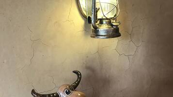 Una pared rústica con textura agrietada, un farol de metal con asa, y una pequeña figurina de burro sobre una tabla de madera.