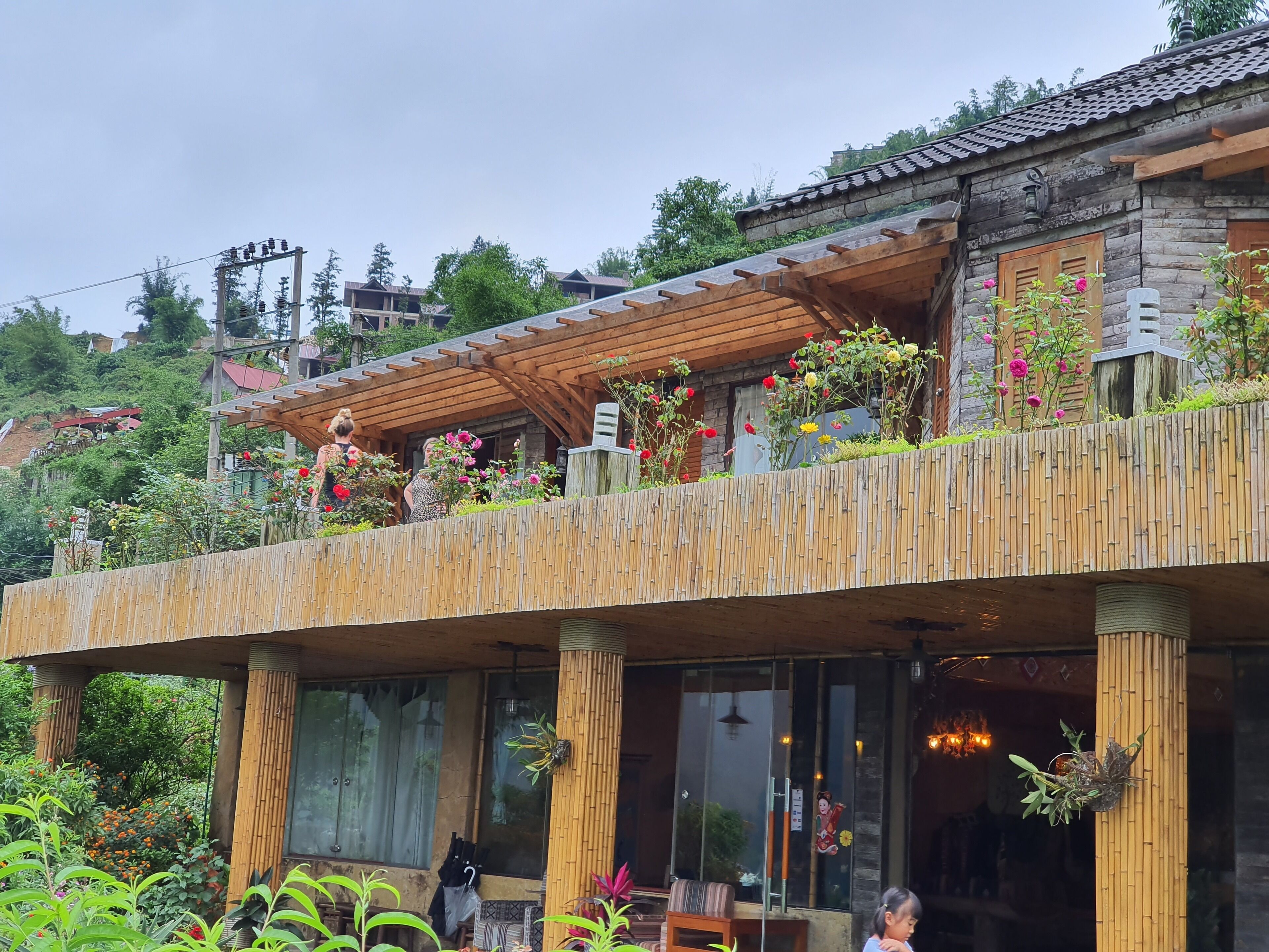 Un bâtiment rustique en bois, doté d’un balcon orné de fleurs et de plantes.