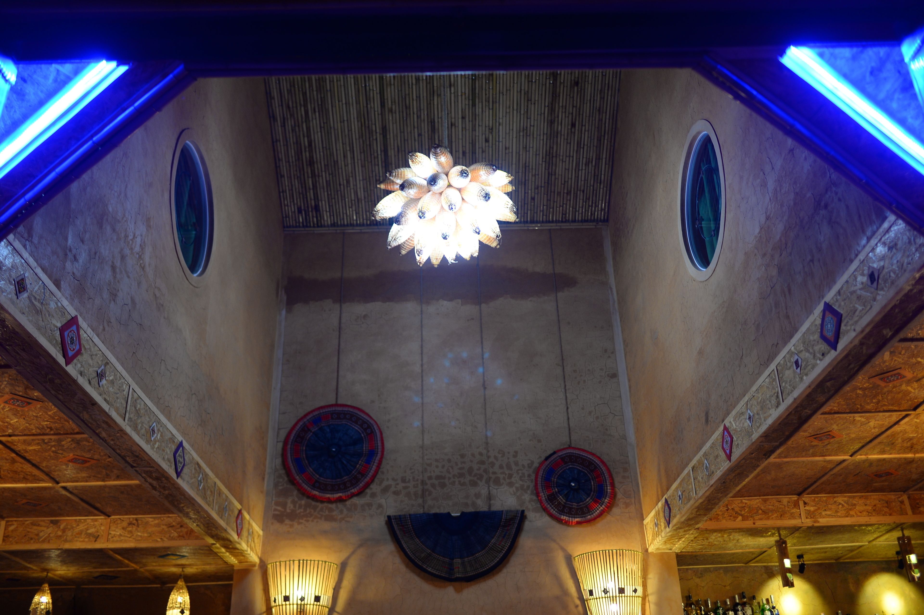 Un soffitto con un lampadario centrale, pannelli murali decorativi e illuminazione a incasso.