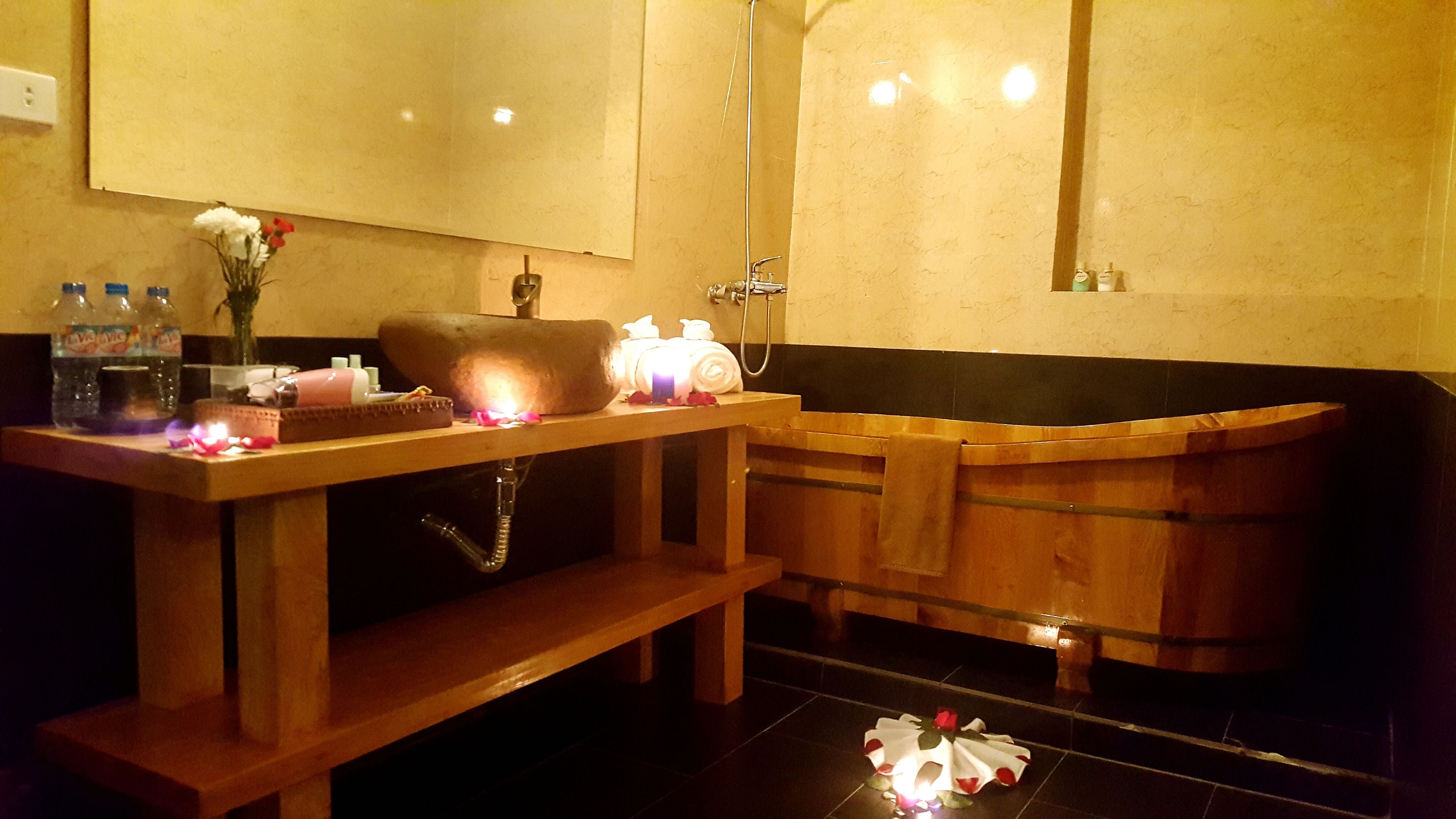 A bathroom with a wooden vanity, a large mirror, and a bathtub.