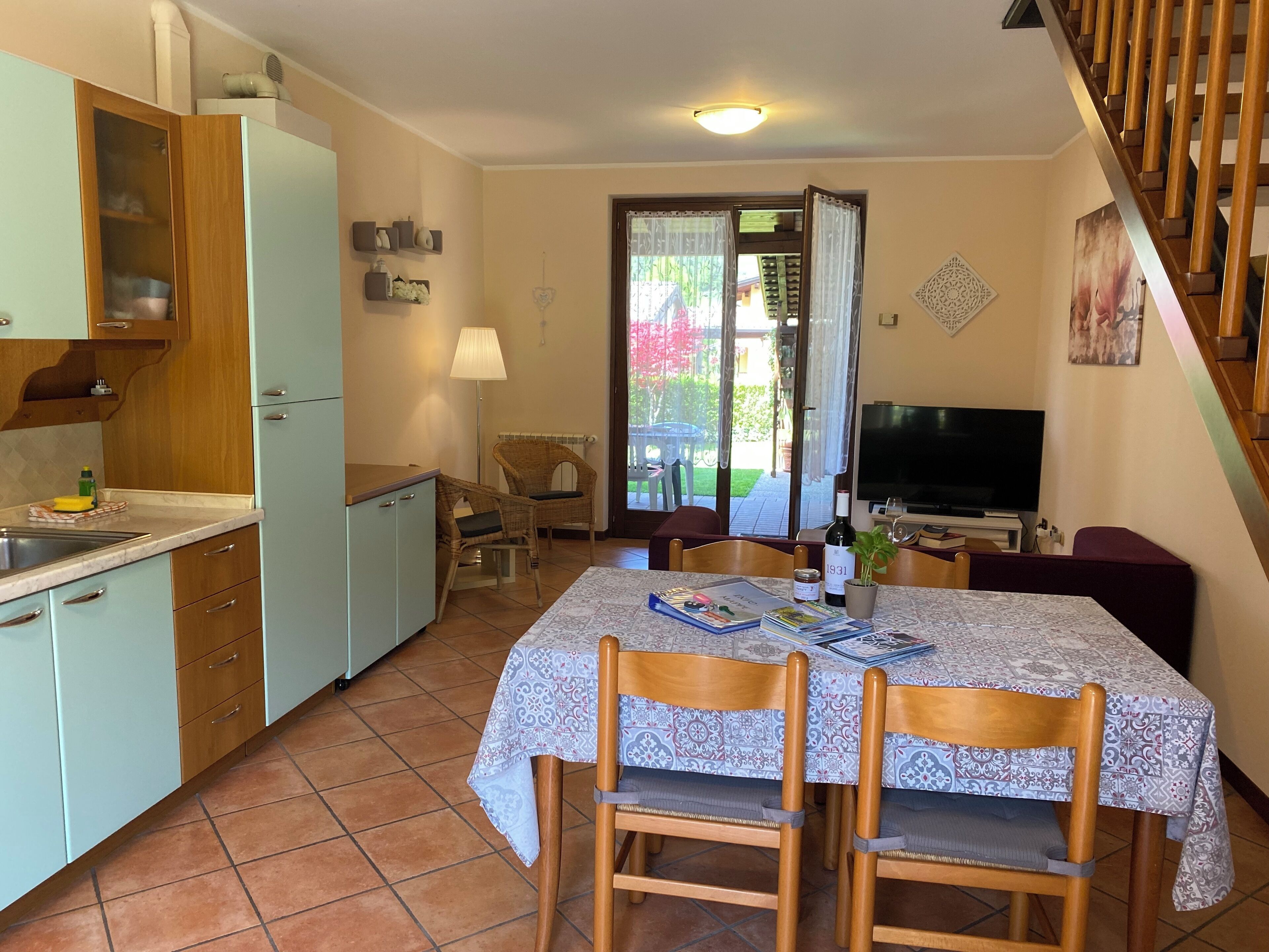 Una cocina compacta con comedor, televisor y escalera.