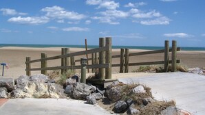 A wooden beach fence with a concrete walkway leading to the beach. - Stylish house with medit. Garden, AC, barbecue, private + heated. Pool and W-Box (Portiragnes)
