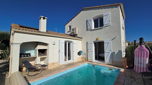 Uma casa de dois andares com piscina, área de estar externa e churrasqueira.