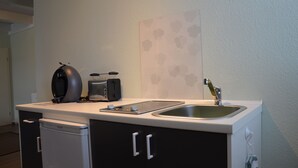 A compact kitchenette with a coffee maker, toaster, and sink.