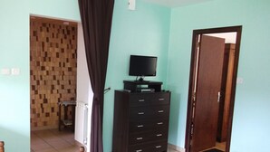 A room with a wooden dining table, a dark wooden dresser, a black television on top, and a black sofa. - Le Moulin de Bouvacôte (Le Tholy)