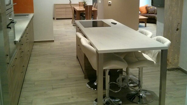 Una cocina moderna con una isla central, armarios de madera y una zona de comedor con mesa y sillas.