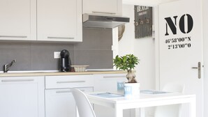 Una cocina moderna con armarios blancos, una cafetera y una mesa de comedor con sillas.
