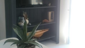 Una sala moderna con un mueble de entretenimiento de madera oscura, una mesa blanca y una planta en maceta.