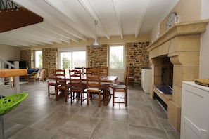 A spacious dining area with a stone fireplace, wooden dining table, and chairs.