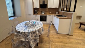 Una cocina moderna con armarios blancos, encimera de madera y un comedor con mesa dispuesta para dos.