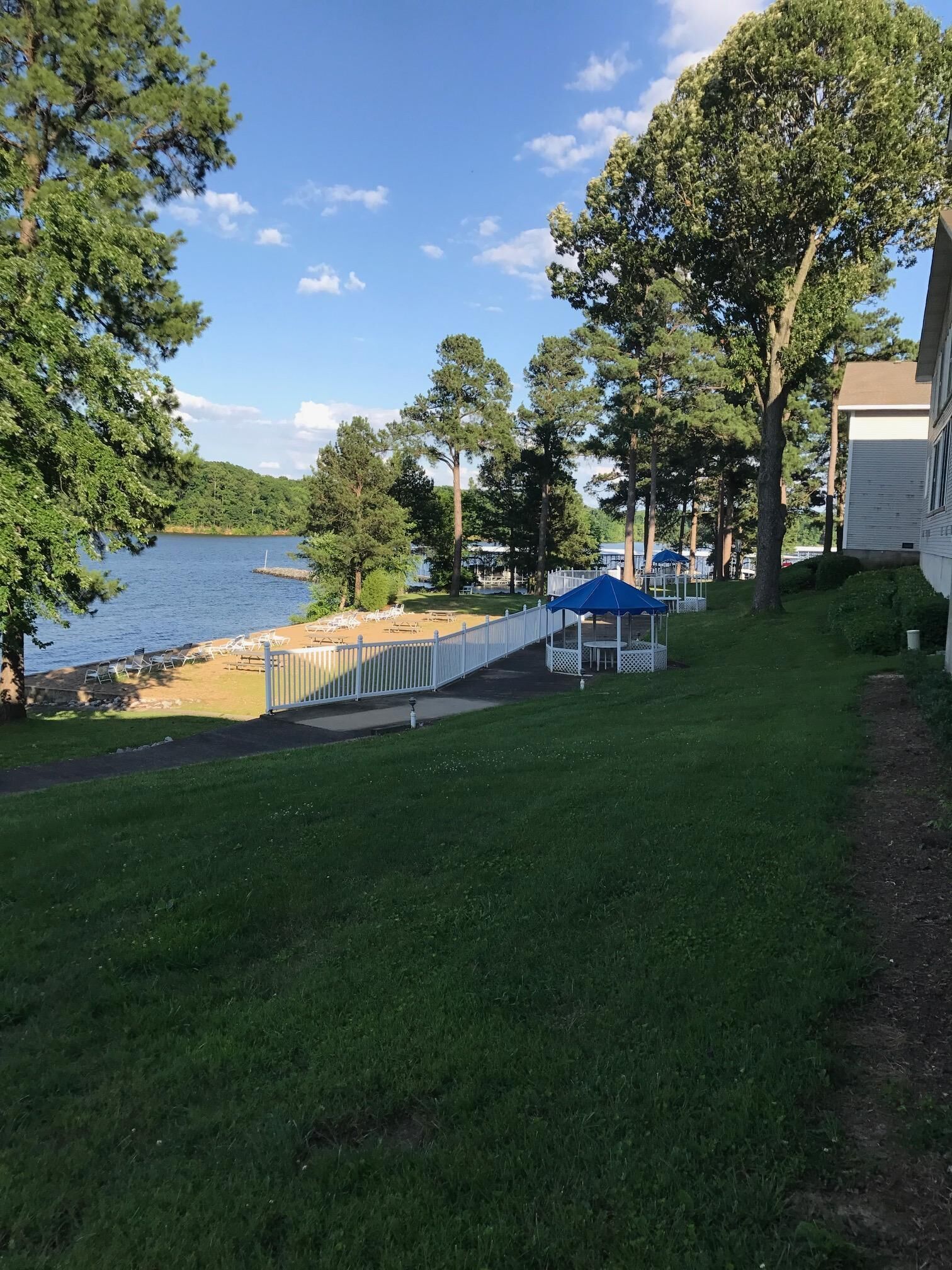 Une propriété au bord du lac, dotée d’une pelouse verdoyante, d’une clôture blanche et d’une jetée qui s’avance dans l’eau.
