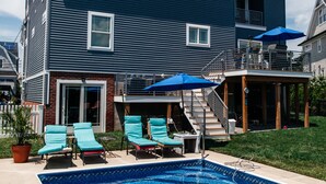 Une maison à deux étages dotée d’une piscine, d’un espace salon extérieur et d’un patio couvert.