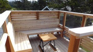 Una terraza de madera con un banco y una pequeña mesa.