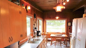 Una cocina con armarios de madera, un lavamanos, una cafetera y una mesa de comedor con sillas.