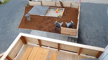 Relax and play in this rooftop patio area with a garden bed, sandbox, slide, and seating for two.