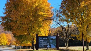 A sign for Harpers Ferry National Historical Park with a grassy foreground and autumn-colored trees. - Shenandoah Paradise – Best River & Mountain Views in Harpers Ferry
 (Harpers Ferry)