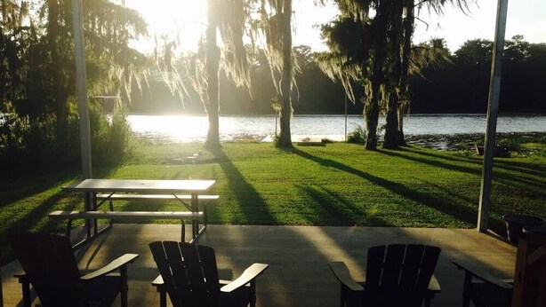 An outdoor seating area with a view of a lake, surrounded by trees and a picnic table.