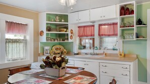 Een keuken met witte kasten, een houten eettafel met placemats en een plafondventilator.