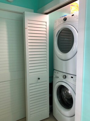 A laundry room with a closed white door and two stacked front-loading washing machines. - Unique Home with loft @ Truman Annex (Key West)
