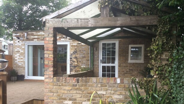 A brick house with a covered porch, a sliding glass door, and a window with a view of the garden. - Garden bungalow - dog friendly (Bushey)