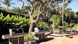Un patio al aire libre con dos asadores portátiles y una mesa lista para comer.