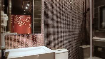 Um banheiro moderno com painel de azulejos, pia branca, vaso sanitário e box de vidro.