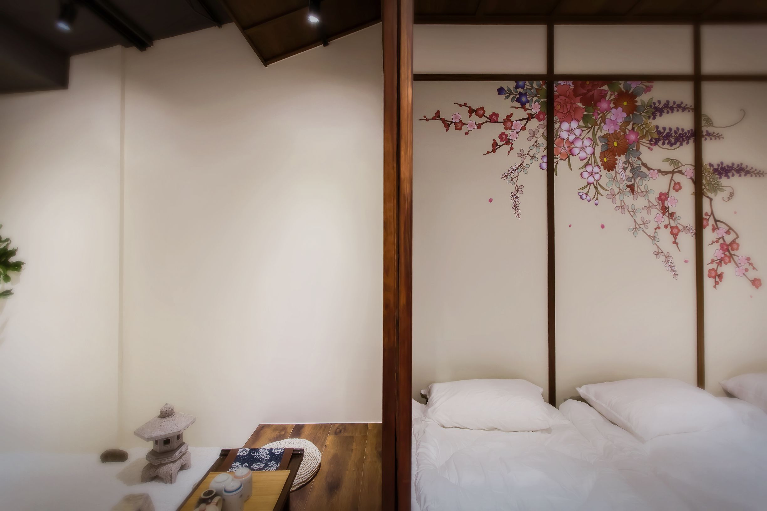 A room with a bed, a small table with a decorative item, and a wall with a floral design.