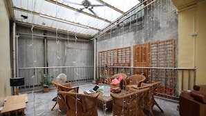 A covered outdoor seating area with wicker furniture, a laptop, and decorative lights. - Movie Inn Hostel (Taichung)