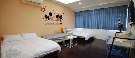 A hotel room with two beds, a desk, and a ceiling fan.