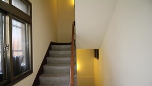 A staircase with carpeted steps and wooden handrails, leading to a landing with a light fixture. - Movie Inn Hostel (Taichung)