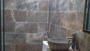 Un baño con inodoro, un lavamanos grande y un cubo de basura pequeño.