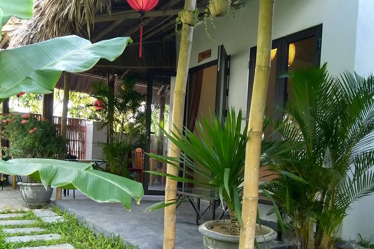 A covered outdoor area with stone steps, potted plants, and a red lantern.