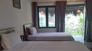 Un dormitorio con dos camas, una ventana con cortinas e iluminación colgante.