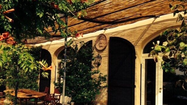 An outdoor patio with a table and chairs, surrounded by potted plants and a wooden pergola. - Villa Monia (Bettola)