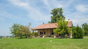 A house with a red-tiled roof, surrounded by a grassy lawn and trees. - Villa Monia (Bettola)