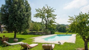 A backyard with a swimming pool, lounge chairs, and a dog. - Villa Monia (Bettola)