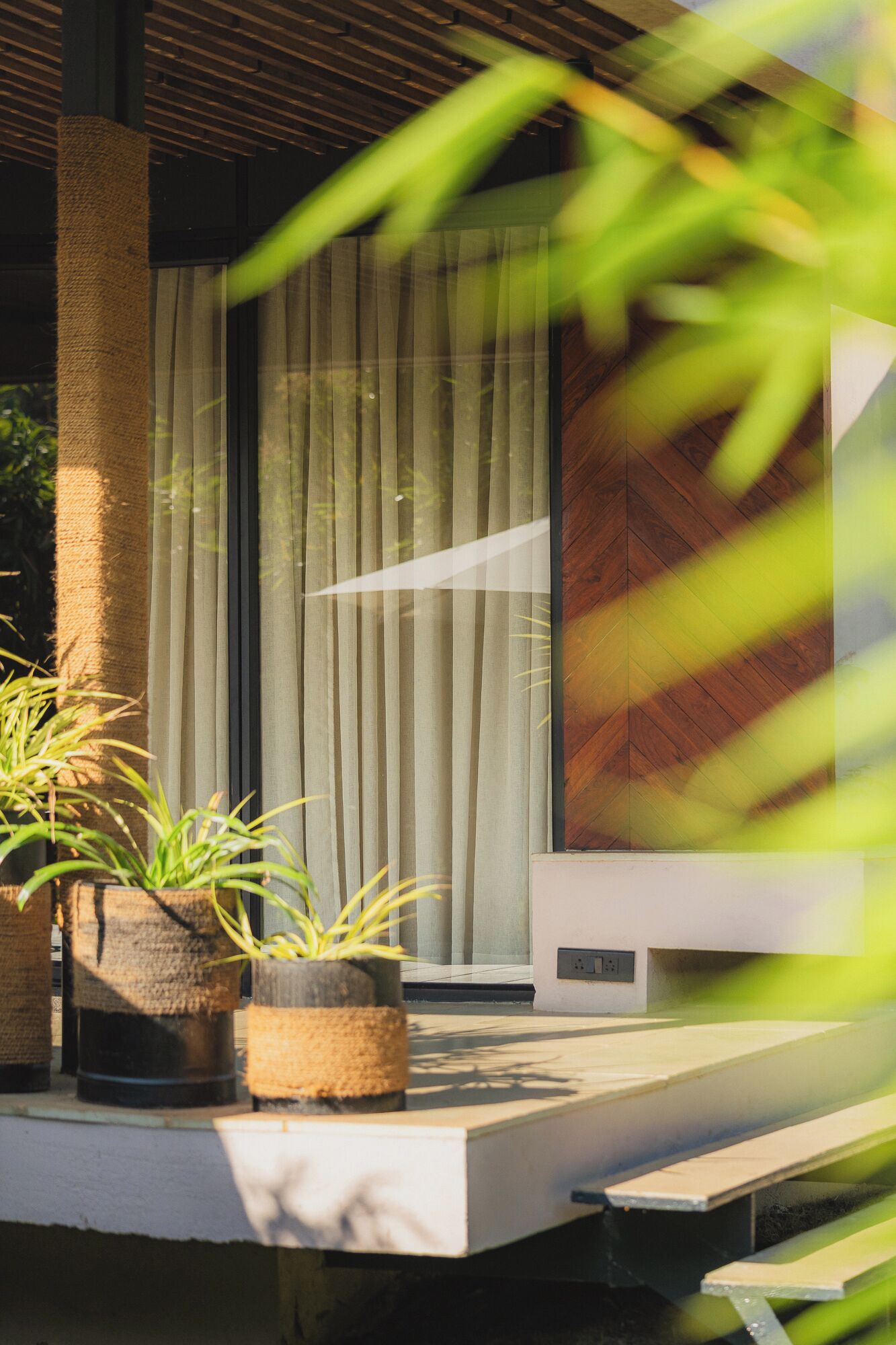 A modern outdoor area with a concrete bench, a vertical garden, and a large window with vertical blinds.